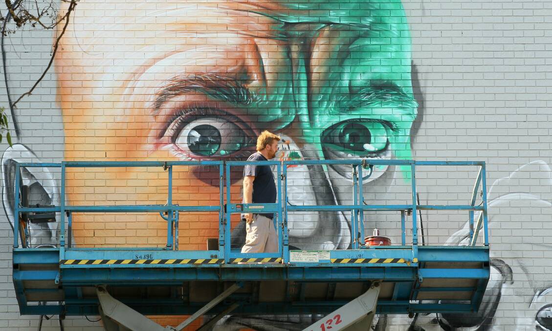 The artist known as Smug gets busy creating his wonderwall on the Wollongong Myer building. Picture: KIRK GILMOUR