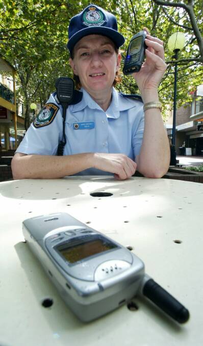 Senior Constable Denise Mair shows how easy it is for a thief to get close enough to slip a mobile phone off a cafe table.