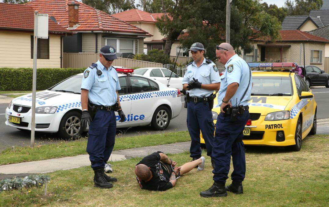 Police stand guard over a man arrested in Fairy Meadow yesterday. 
