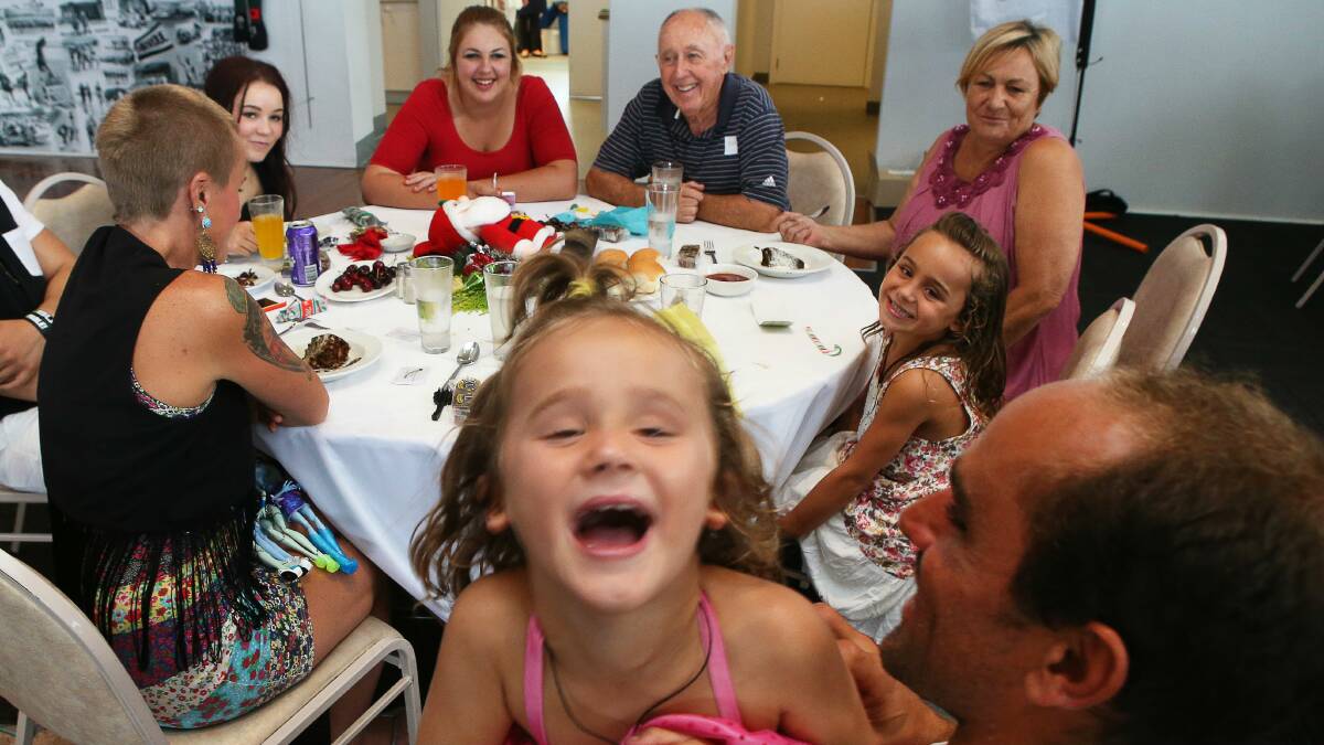 Leo Loro tickles daughter Talita at the Thirroul Surf Club festive feast set up by John and Fay Kosten. Picture: KIRK GILMOUR