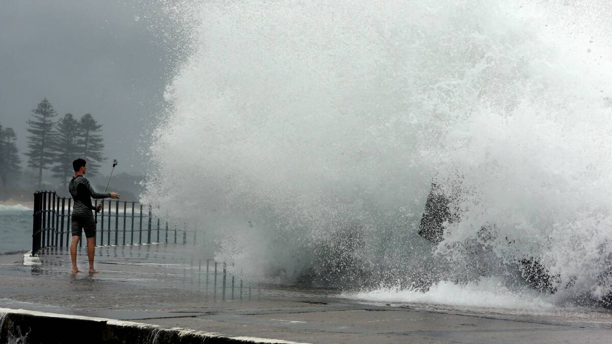 Now you don't...a man at Wollongong Harbour films his mate being swamped by heavy surf. Pictures: ROBERT PEET