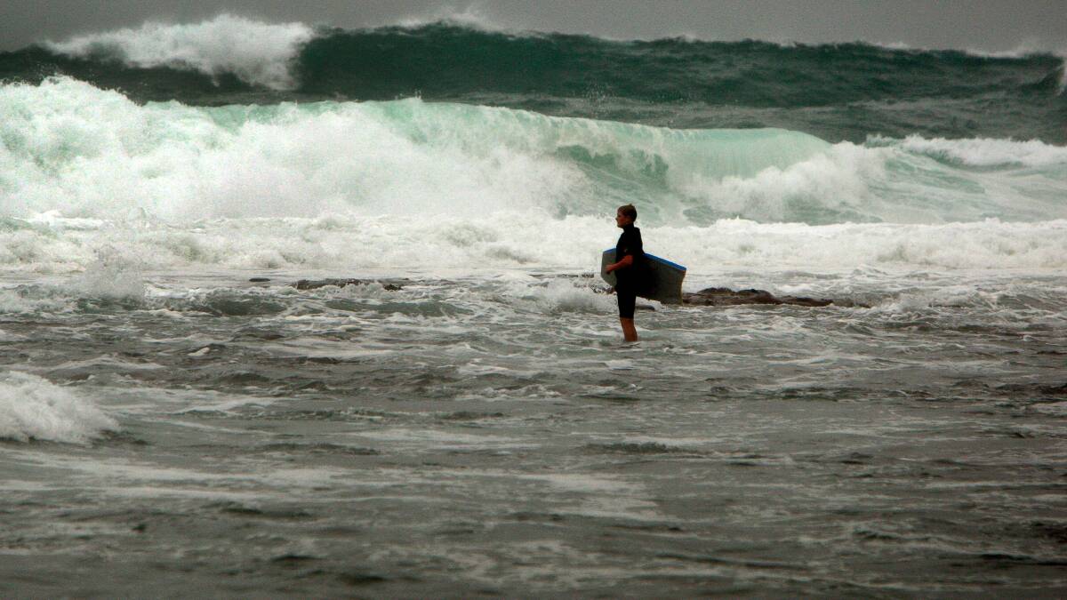 A bodyboarder at Barrack Point checks the heavy surf before deciding to head out. Picture: SYLVIA LIBER