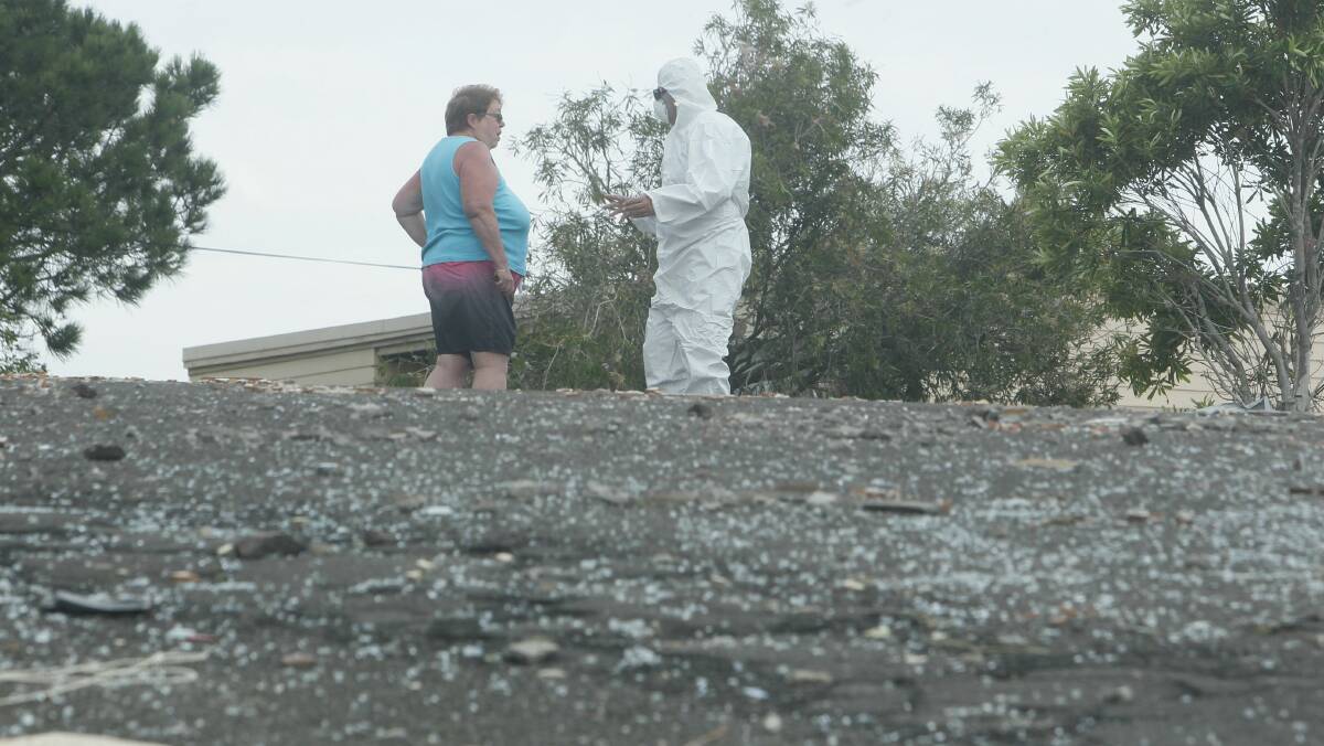 An asbestos specialist explains the dangers to a resident in Minnamurra Street yesterday. Picture: DAVID TEASE